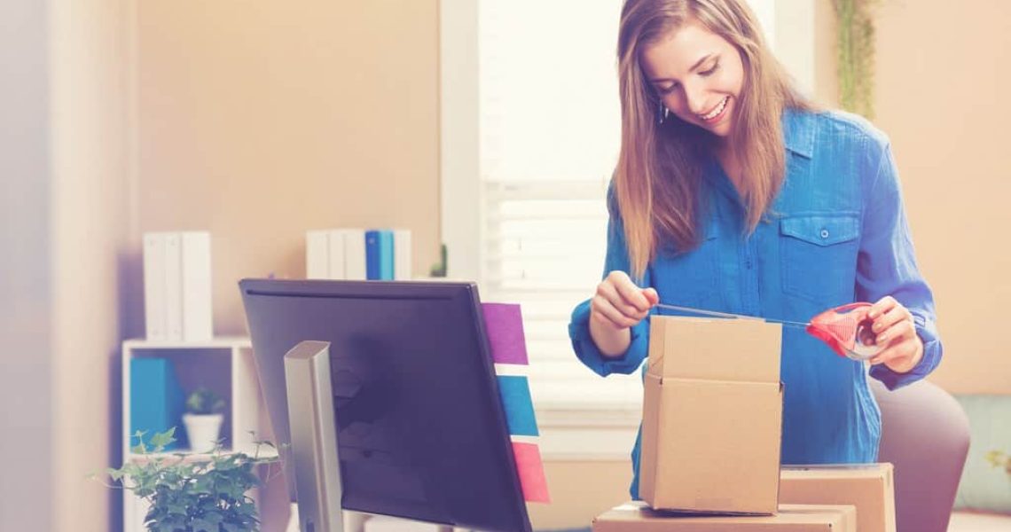 Young woman taping boxes to be shipped in her home office