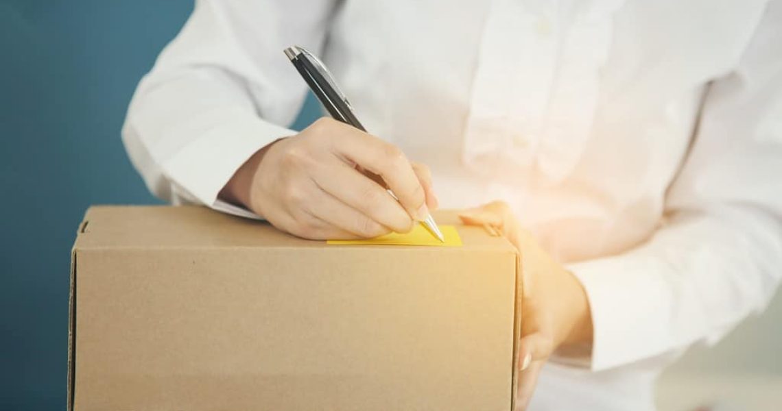 Delivery Concept, Young Asian woman working online shopping at home office.Young woman writing note on parcel at warehouse, closeup.